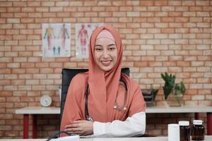 portret van een mooie vrouwelijke arts, mooie moslim in uniform met een stethoscoop, glimlachend en kijkend naar de camera in de kliniek van het ziekenhuis. één persoon met expertise in professionele behandeling.
