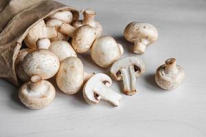 champignons champignons in papieren zak op een witte houten tafel. plaats voor tekst of reclame. bovenaanzicht foto