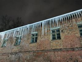 winteravond ijspegels hangend aan het dak in het licht van een lantaarn foto