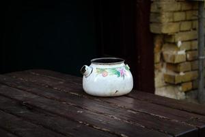 oude kapotte waterkoker die op een houten tafel staat foto