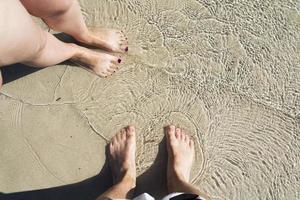 twee paren op het zand met zeewater. foto