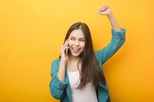 mode portret van mooie vrouw in groen pak met behulp van mobiele telefoon op gele achtergrond foto