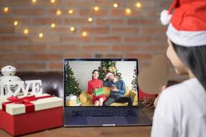 jonge lachende vrouw met rode kerstman hoed video bellen op sociaal netwerk met familie en vrienden op eerste kerstdag. foto