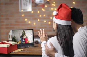 jong stel met een rode kerstmuts die op eerste kerstdag videogesprek voert op sociaal netwerk met familie en vrienden. foto