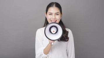 mooie aziatische vrouw met megafoon op grijze achtergrond studio foto