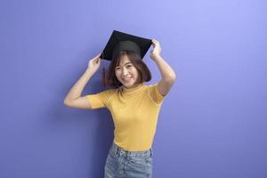 portret van een jonge Aziatische student die een afstudeerpet draagt over de achtergrond van de studio. foto