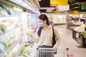 vrouw winkelt in supermarkt met gezichtsmasker foto