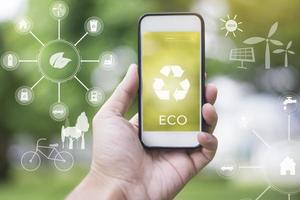close-up man hand met smartphone op groen met ecologische pictogrammen, save earth concept