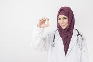mooie vrouw arts met hijab houdt vaccin op witte achtergrond