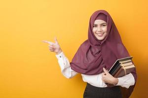 mooie universiteitsstudent met hijab portret op gele achtergrond foto