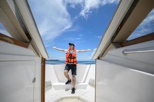 toerist in reddingsvest genieten en ontspannen op speedboot met een prachtig uitzicht op de oceaan en de bergen in achtergrondkleur foto