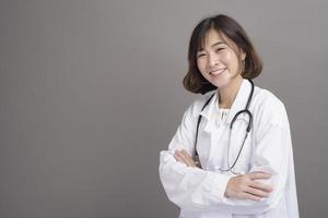 portret van jonge zelfverzekerde vrouw arts geïsoleerd over grijze achtergrond studio foto