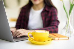 hete latte-kunst in gele kop op bureau foto