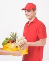 portret van een man in rood uniform houdt vers voedsel in plastic doos op witte achtergrond, thuisbezorgingsconcept foto