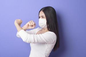 portret van een jonge vrouw draagt een gezichtsmasker op een paarse achtergrond foto