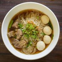 bovenaanzicht van Thais eten noodle in kom op houten tafel foto