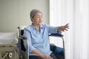 depressieve en hopeloze Aziatische kankerpatiënt vrouw met hoofddoek in het ziekenhuis.
