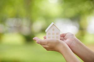 close-up vrouw hand houdt huis op groene achtergrond foto