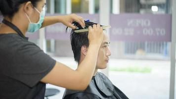 een jonge man wordt geknipt in een kapsalon, salonveiligheidsconcept foto