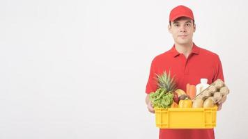 portret van een man in rood uniform houdt vers voedsel in plastic doos op witte achtergrond, thuisbezorgingsconcept foto