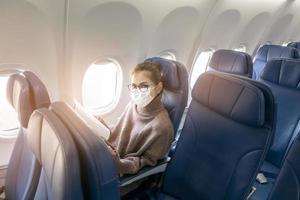 een jonge vrouw met een gezichtsmasker reist met het vliegtuig, nieuw normaal reizen na covid-19 pandemisch concept