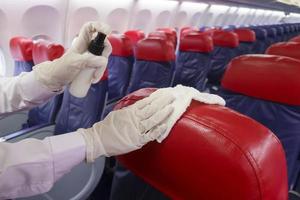 close-up hand draagt handschoenen die vliegtuigstoel schoonmaken voor covid-19 preventie pandemie foto
