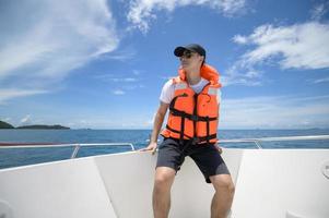 toerist in reddingsvest genieten en ontspannen op speedboot met een prachtig uitzicht op de oceaan en de bergen in achtergrondkleur foto