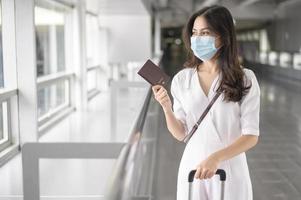 een reizigersvrouw draagt een beschermend masker op de internationale luchthaven, reist onder covid-19 pandemie, veiligheidsreizen, protocol voor sociale afstand, nieuw normaal reisconcept