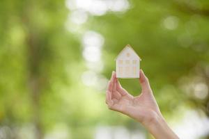 close-up vrouw hand houdt huis op groene achtergrond foto