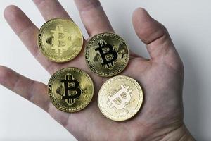 hand met vier bitcoin op een witte achtergrond. foto