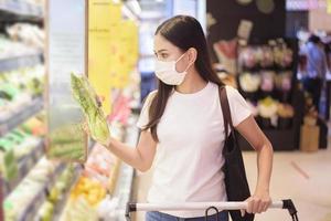 vrouw winkelt in supermarkt met gezichtsmasker foto