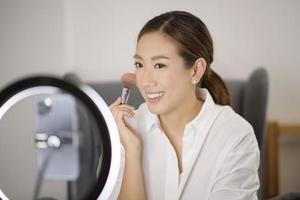 een mooie Aziatische make-upblogger streamt live hoe je gezichtsmake-up kunt maken in haar huis-, schoonheids- en technologieconcept foto
