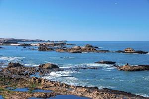 rotsformaties aan de kustlijn in zee tegen blauwe heldere hemel foto