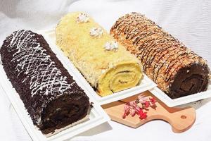 Spons cake roll plakjes geïsoleerd op een witte achtergrond, met chocolade, vanille en bessen crème, verschillende Zwitserse broodjes collectie foto