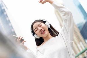 gelukkig lachend Aziatisch meisje dat naar muziek luistert op een koptelefoon foto