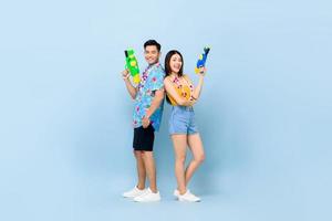 jong Aziatisch stel in zomeroutfits met waterpistolen op studio blauwe achtergrond voor songkran-festival in Thailand en Zuidoost-Azië foto