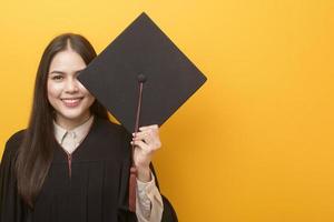 portret van gelukkige mooie vrouw in afstudeerjurk op gele achtergrond foto