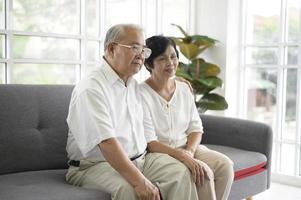 bejaarde Aziatische echtpaar televisie kijken zittend op een bank foto