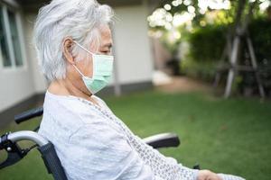 aziatische senior of oudere oude dame vrouw op rolstoel en het dragen van een gezichtsmasker ter bescherming van de veiligheidsinfectie covid-19 coronavirus in park. foto