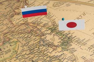 de vlaggen van rusland en japan op de wereldkaart. conceptuele fotografie, politieke verschillen vanwege het eiland Sachalin foto