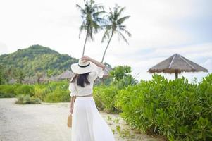 een gelukkige mooie vrouw in een witte jurk die geniet en ontspant op het strand, zomer en vakantie concept