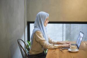 moslimvrouw met hijab werkt met laptopcomputer in coffeeshop foto