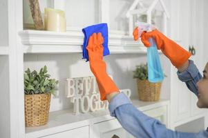 een vrouw met schoonmaakhandschoenen die alcoholspray gebruikt om het huis schoon te maken, gezond en medisch, covid-19 bescherming thuis concept foto