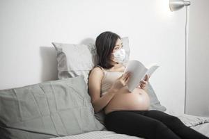 mooie aziatische zwangere vrouw draagt een beschermend masker in haar huis, coronavirusbeschermingsconcept foto