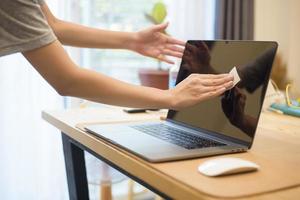 vrouw maakt laptop schoon met alcoholspray foto