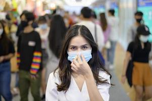 een vrouw draagt een beschermend masker op straat met overvolle mensen terwijl covid-19 pandemie, coronavirusbescherming, veiligheidslevensstijlconcept foto