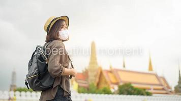 een jonge, mooie aziatische vrouw draagt een beschermend masker dat rond beroemde plaatsen in de stad Bangkok reist, nieuw normaal reizen, covid-19-bescherming, veilige reizen foto