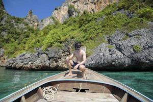 een actieve man op Thaise traditionele longtailboot is klaar om te snorkelen en te duiken, phi phi-eilanden, thailand foto