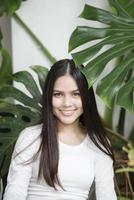 een jonge vrouw in witte kleding portret met groene planten foto