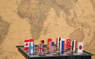 symbolen van landen op het schaakbord tegen tegen de achtergrond de politieke kaart van de wereld. politieke spelletjes. foto